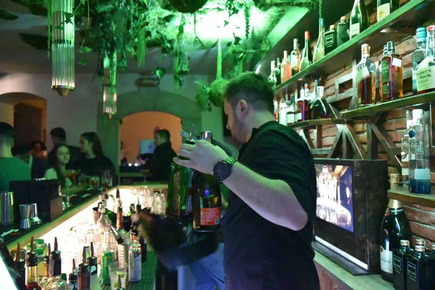 Barmanul toarnă, sub lumină verde